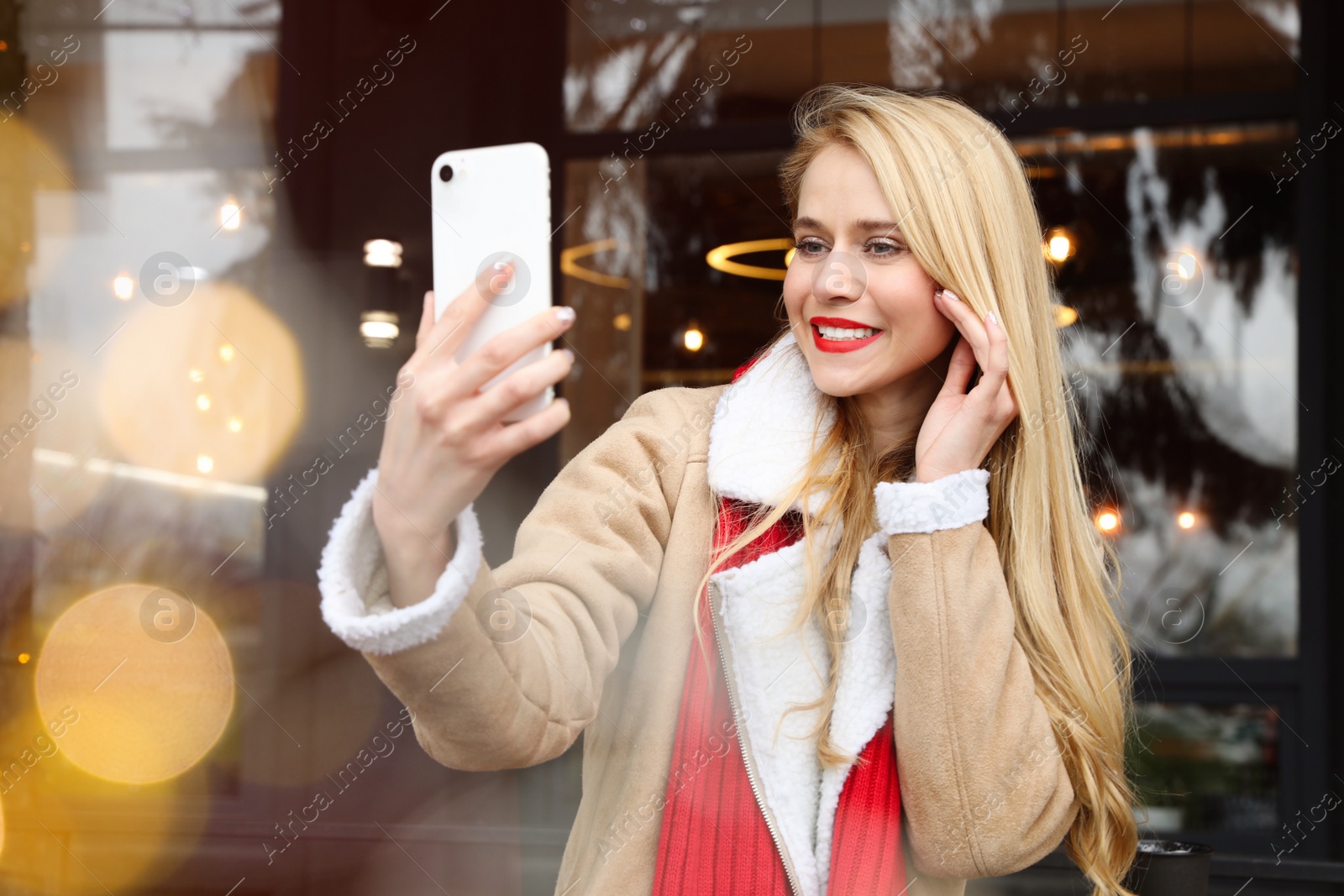 Photo of Young woman taking selfie at winter fair. Christmas celebration