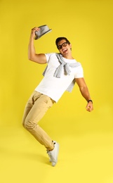 Photo of Handsome young man dancing on yellow background