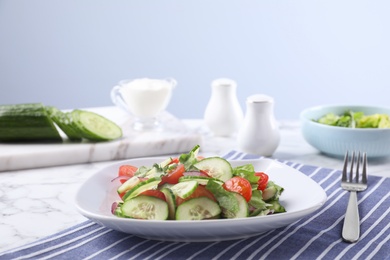 Photo of Plate of vegetarian salad with cucumber, tomato, lettuce and onion served on table