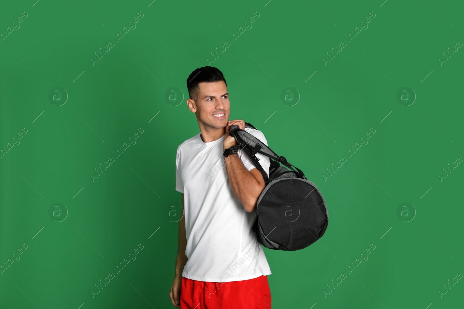 Photo of Handsome man with sports bag on green background