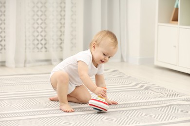 Photo of Children toys. Cute little boy playing with spinning top on rug at home
