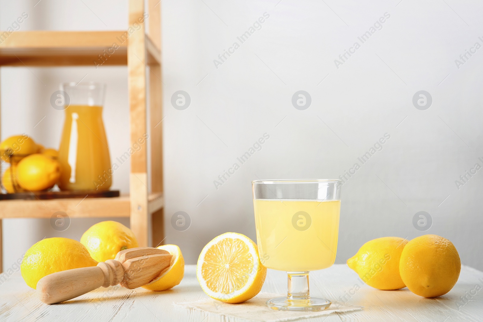 Photo of Glass with fresh lemon juice and fruits on table