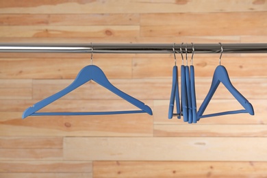 Photo of Metal rack with clothes hangers on wooden background