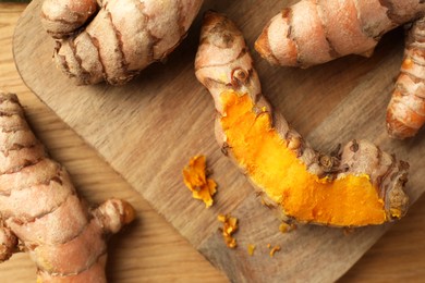 Photo of Many raw turmeric roots on wooden table, flat lay