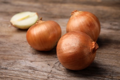 Photo of Ripe onions on rustic wooden table, closeup