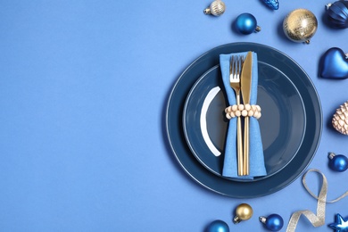 Photo of Beautiful table setting with Christmas ornament on blue background, flat lay. Space for text