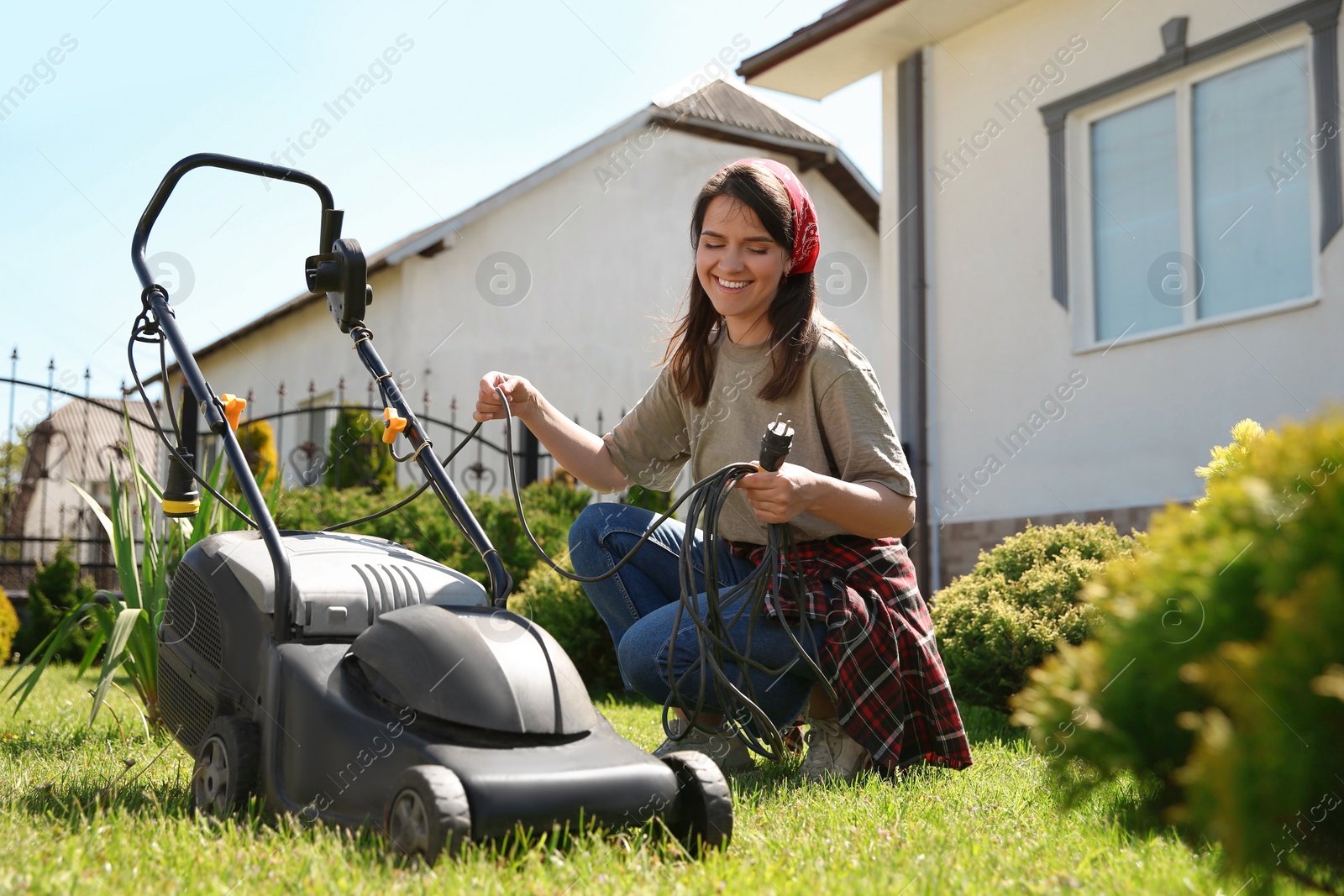 Photo of Smiling woman with modern lawn mower in garden