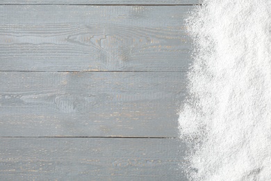 Photo of Artificial snow on light grey wooden background, top view with space for text. Christmas decor