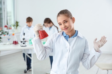 Photo of Schoolgirl holding conical flask at chemistry class