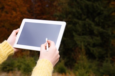 Photo of Woman drawing with graphic tablet near forest in autumn, closeup