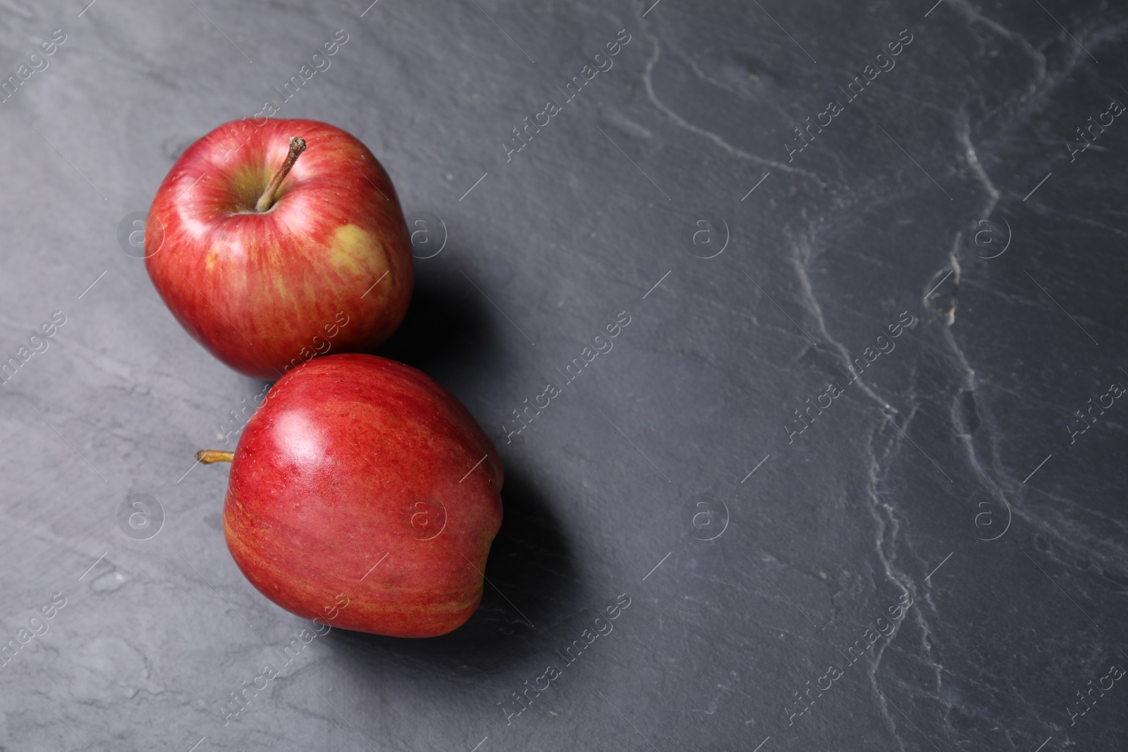 Photo of Ripe red apples on black textured table. Space for text