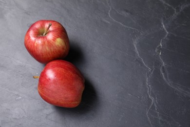 Photo of Ripe red apples on black textured table. Space for text