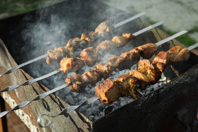 Photo of Cooking delicious meat on metal brazier outdoors