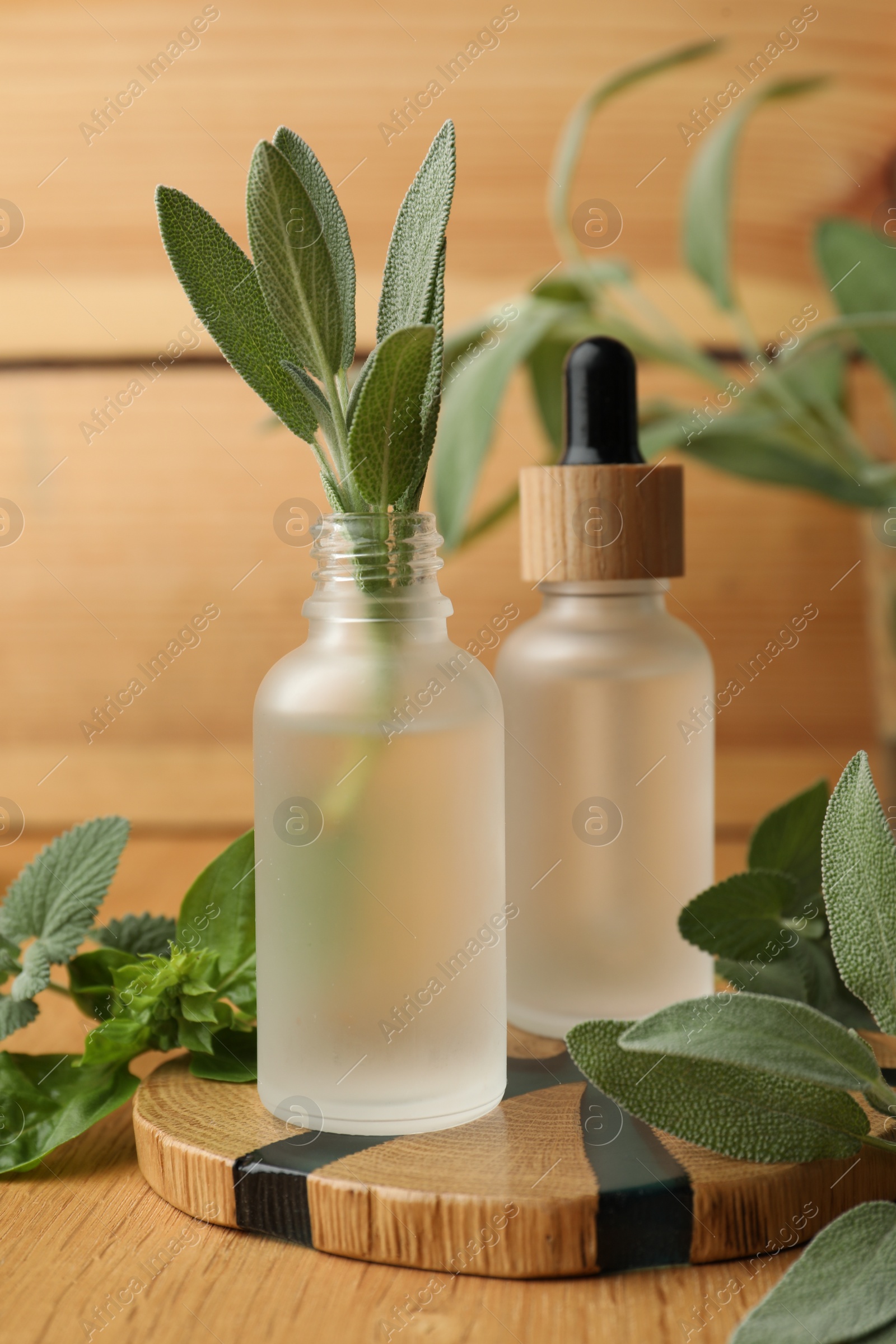 Photo of Bottles of essential oils and fresh herbs on wooden table