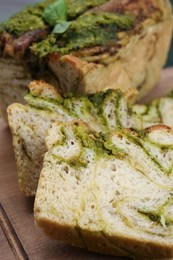 Photo of Freshly baked pesto bread on wooden board, closeup