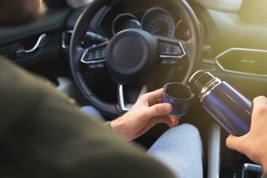Photo of Man with thermos on driver's seat of car, closeup