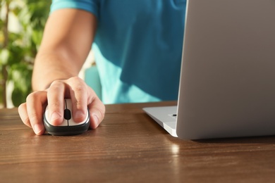 Photo of Man using computer mouse with laptop at table, closeup