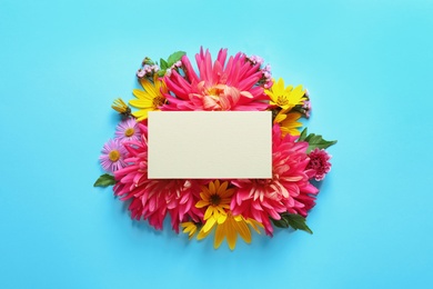 Flat lay composition with beautiful dahlia flowers and blank card on color background