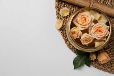 Photo of Tibetan singing bowl with water, mallet and beautiful rose flowers on white background, top view. Space for text