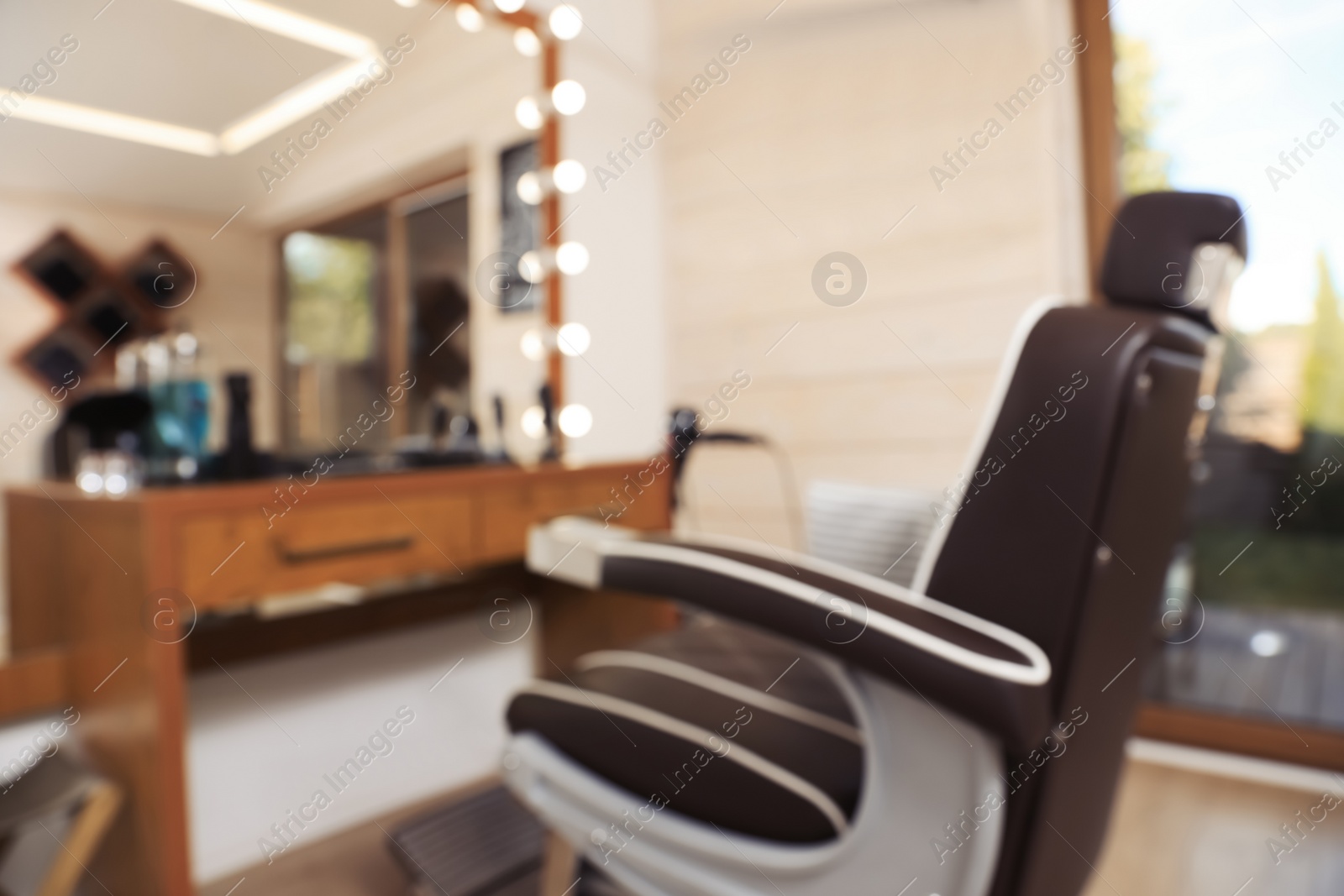 Photo of Blurred view of stylish hairdresser's workplace with professional armchair in barbershop