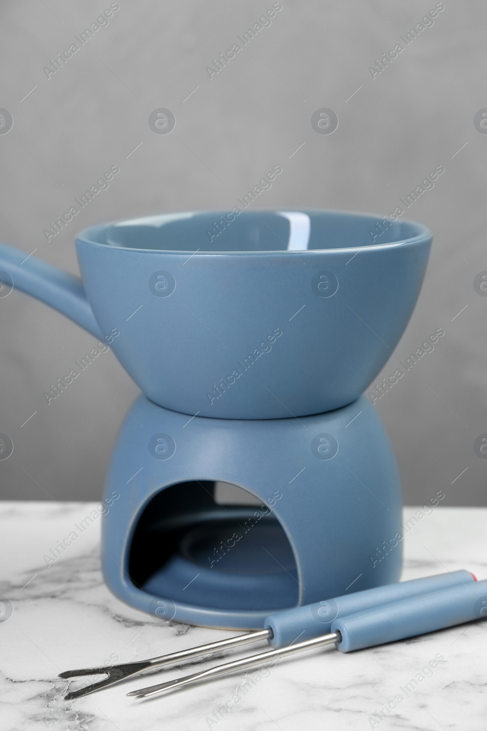 Photo of Fondue set on white marble table against light gray wall