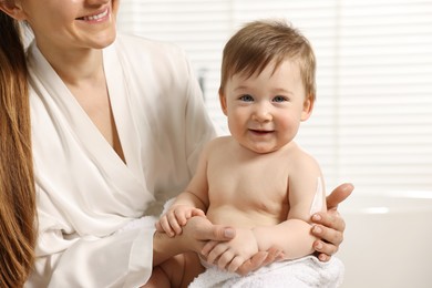 Mother applying body cream onto baby`s skin indoors, closeup