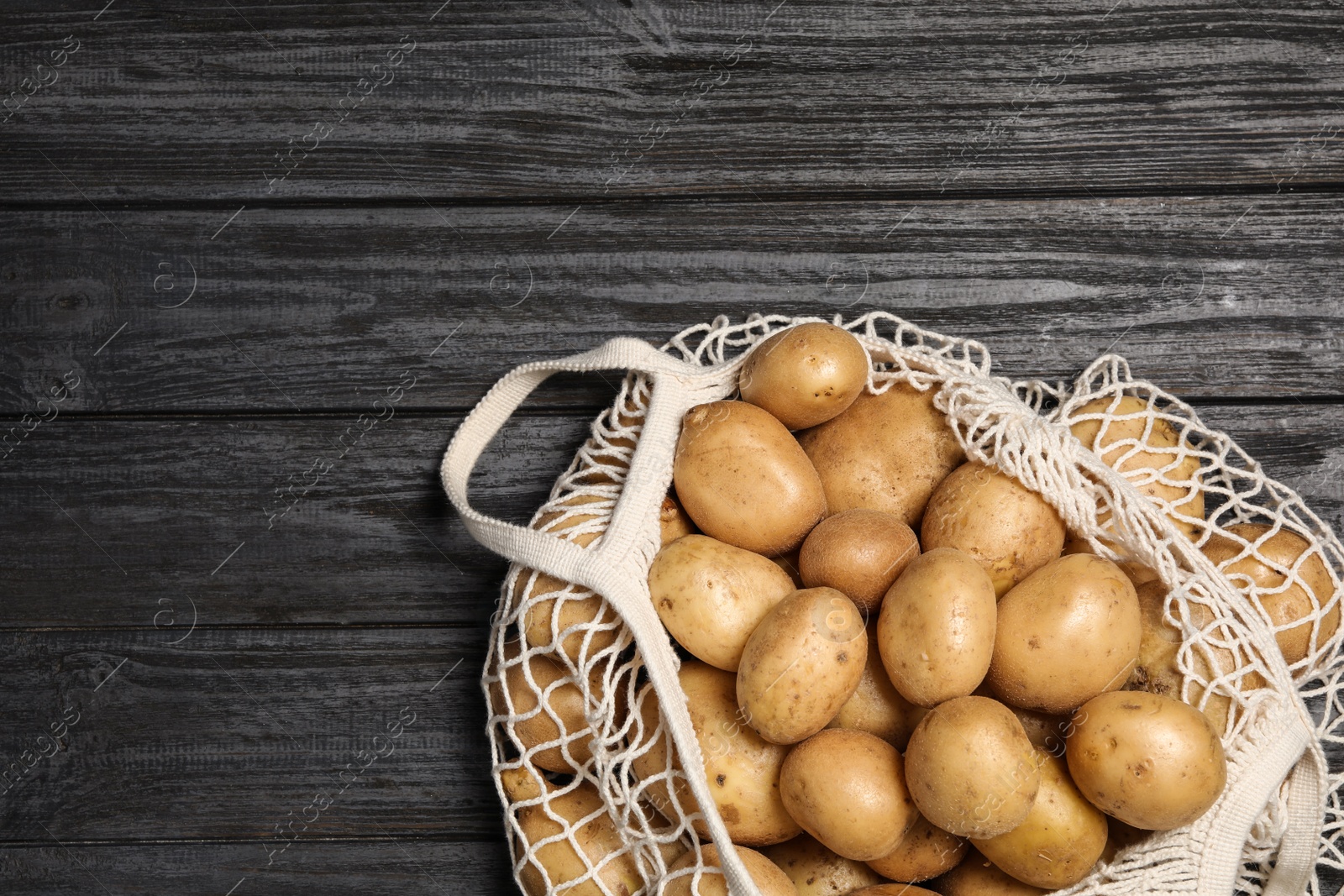 Photo of Raw fresh organic potatoes on black wooden background, top view. Space for text