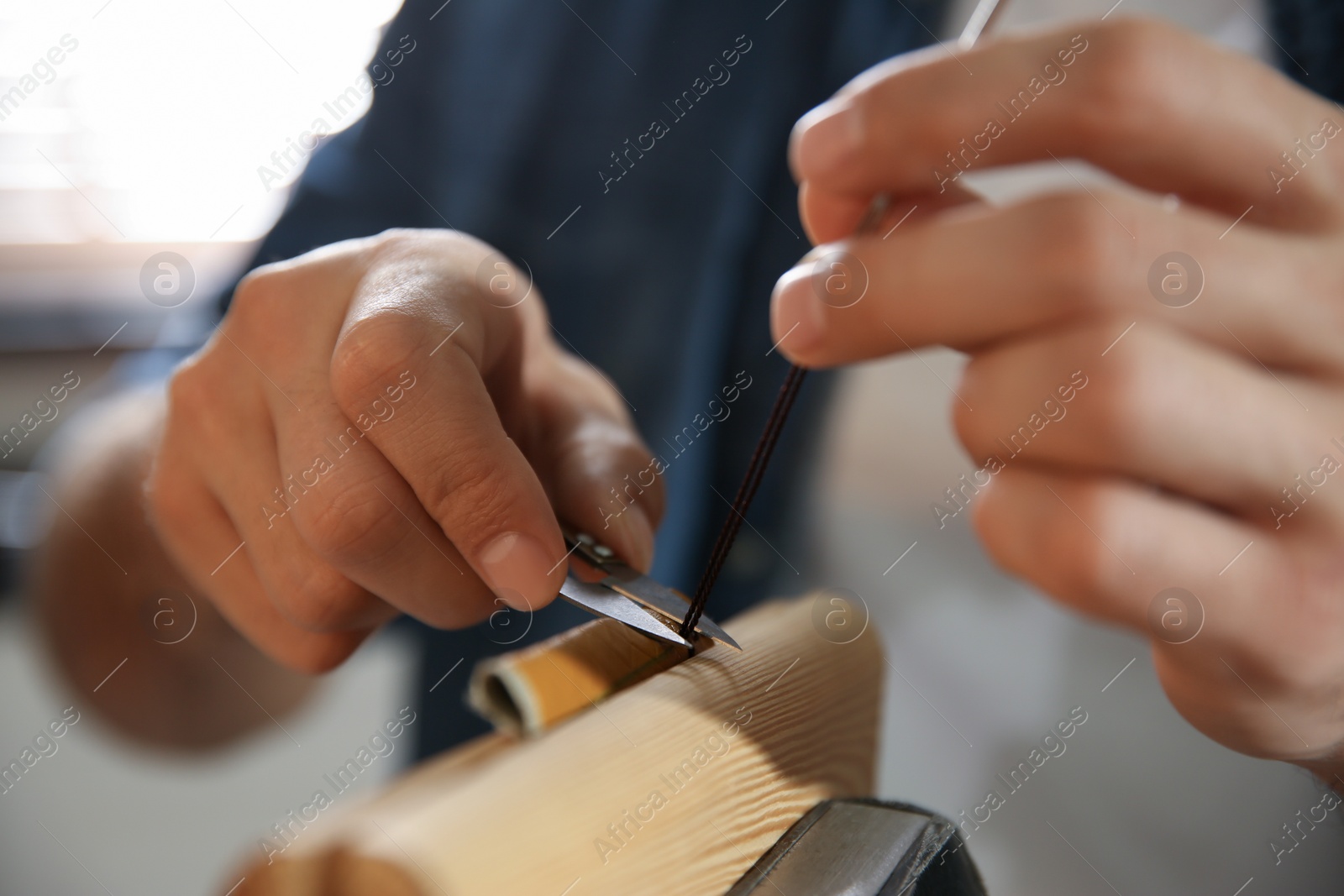 Photo of Man sewing piece of leather in workshop, closeup