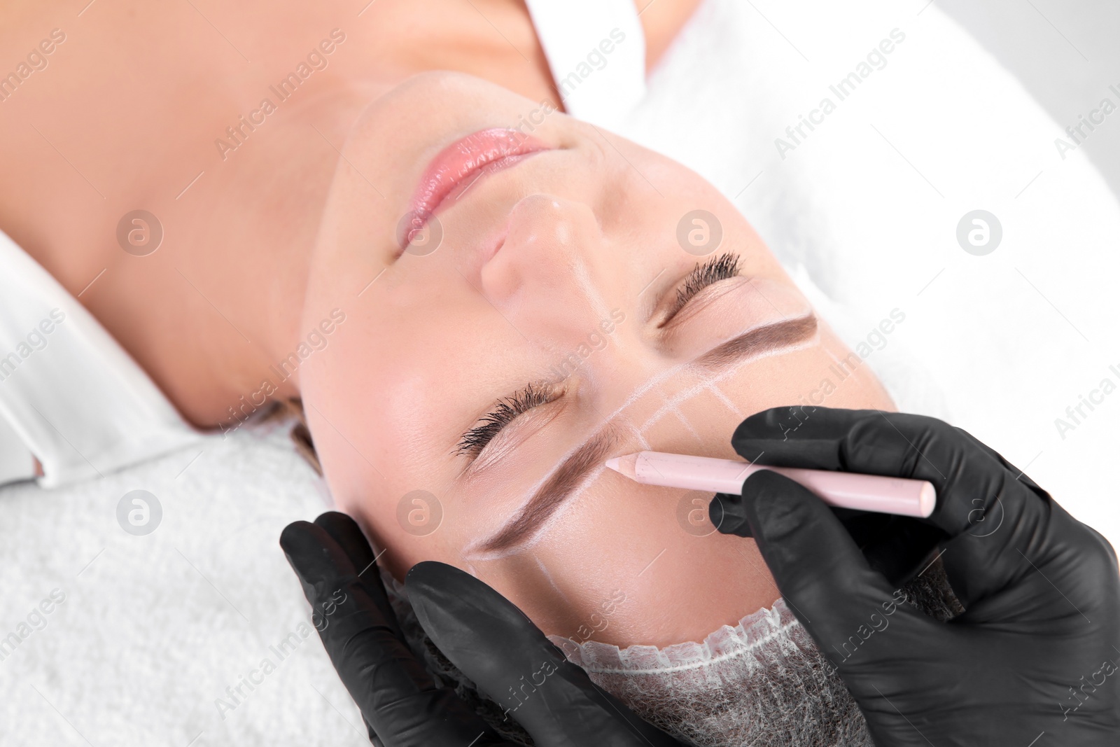 Photo of Young woman undergoing eyebrow correction procedure in salon