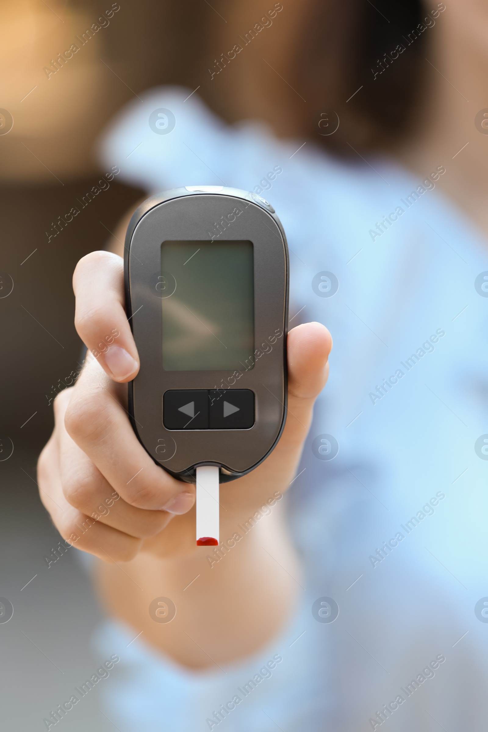 Photo of Woman holding digital glucometer on blurred background. Diabetes control