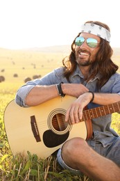 Photo of Portrait of happy hippie man with guitar in field