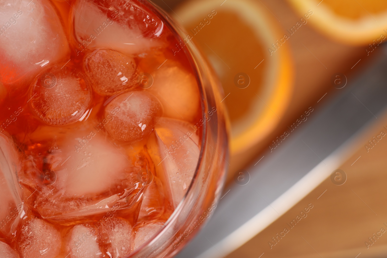 Photo of Aperol spritz cocktail and ice cubes in glass on wooden table, above view