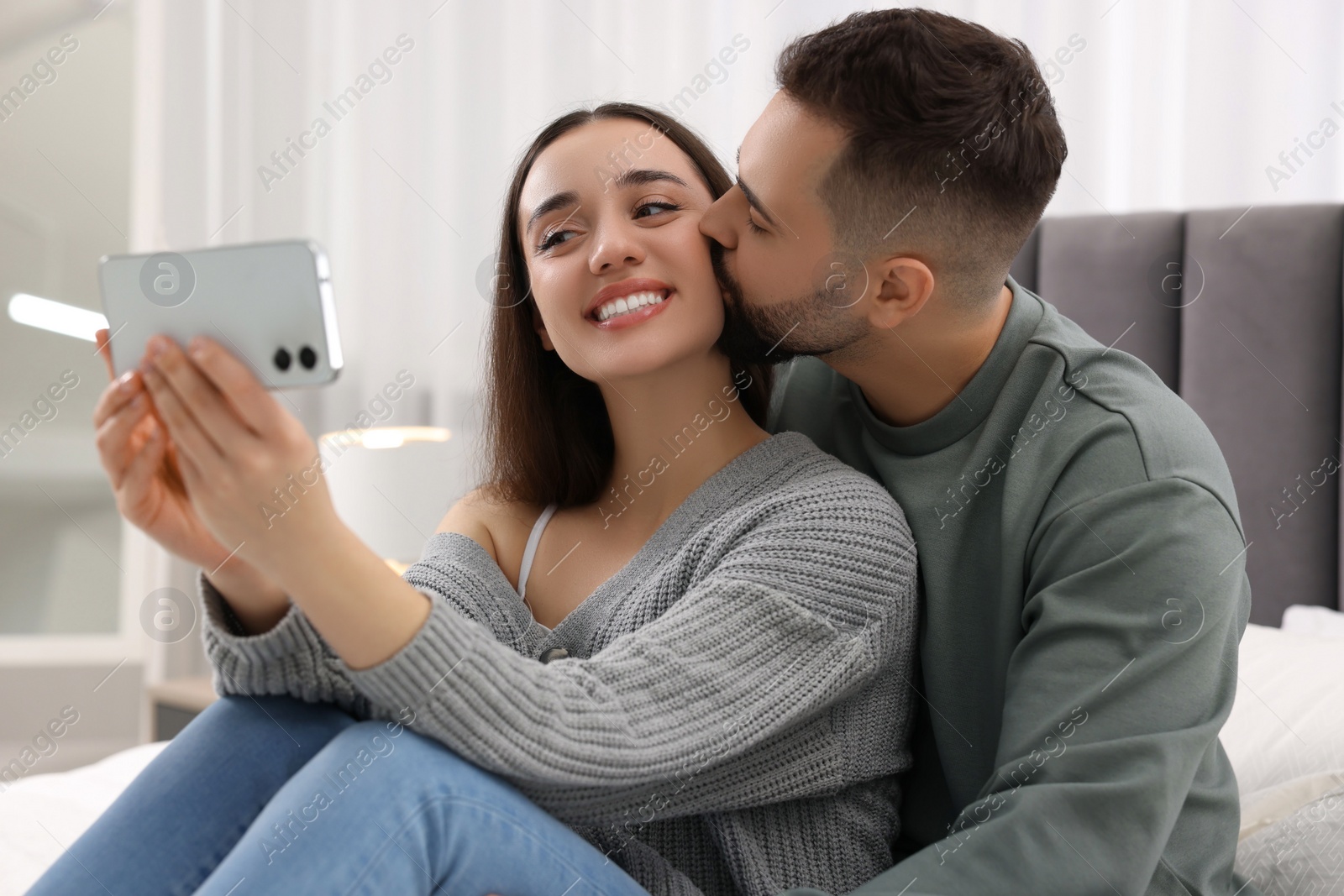 Photo of Happy young couple taking selfie in bedroom