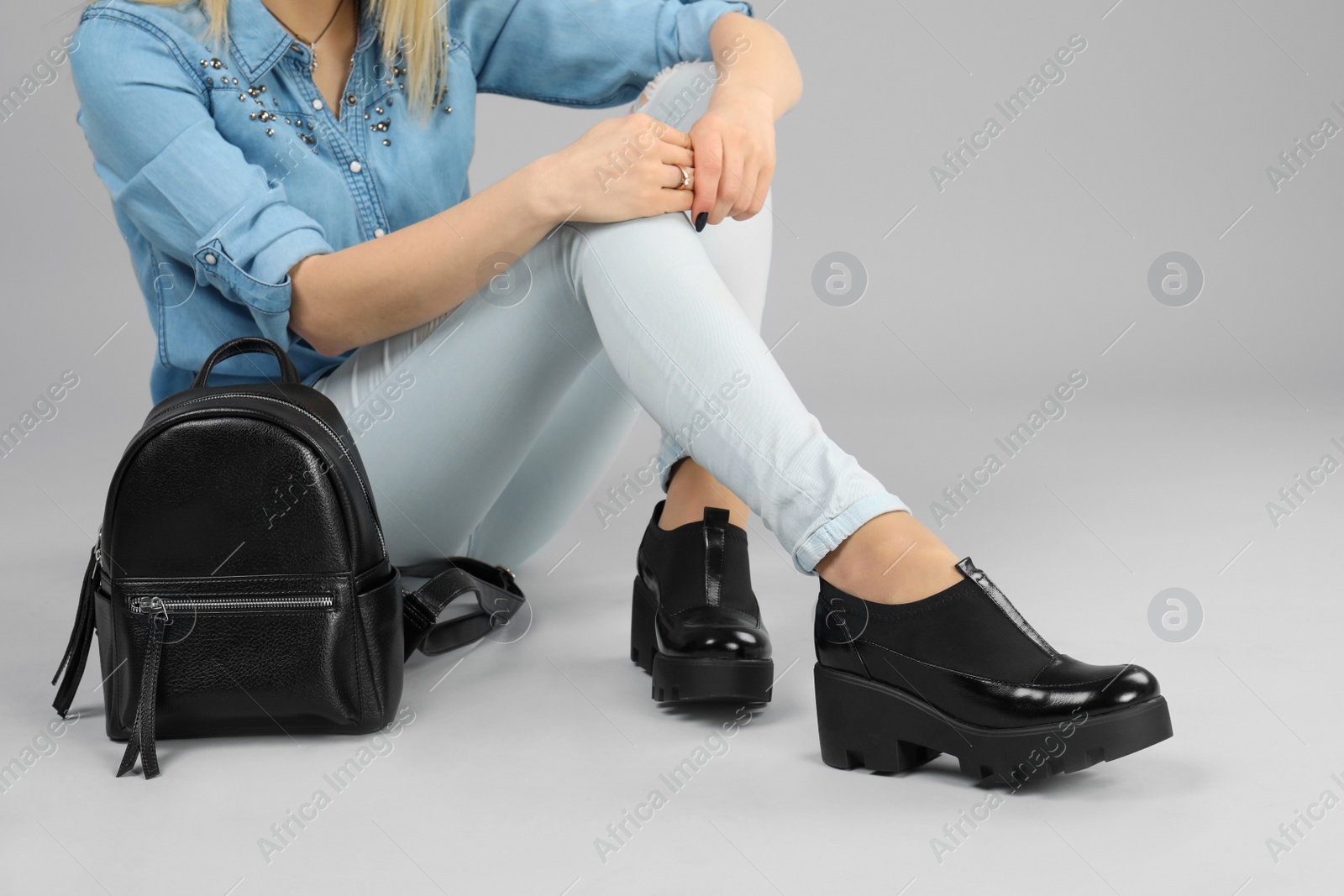 Photo of Woman in elegant shoes with stylish backpack on grey background, closeup