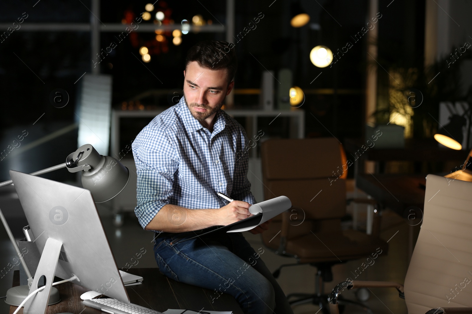 Photo of Young man working in office at night