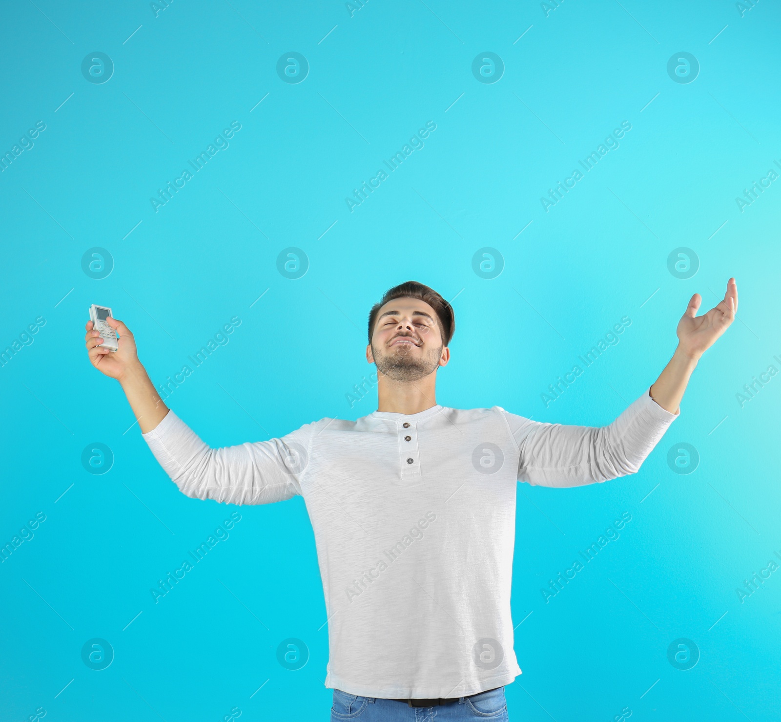 Photo of Happy young man with air conditioner remote on color background