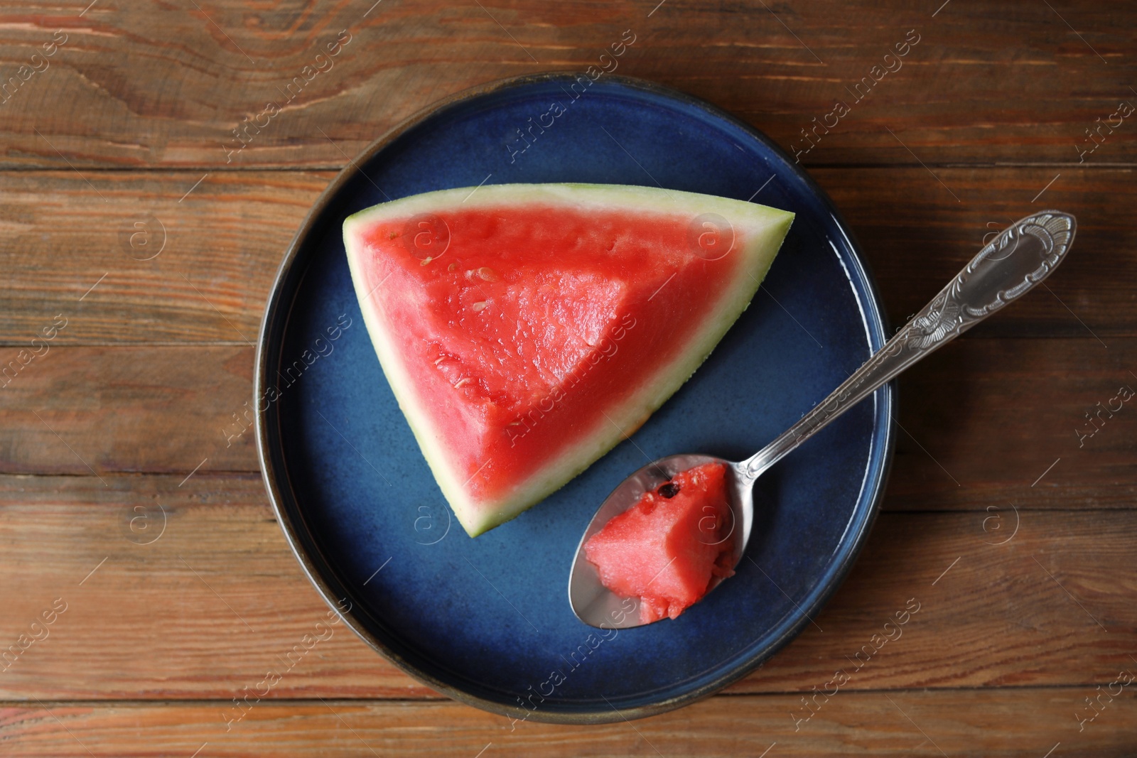 Photo of Sliced fresh juicy watermelon and spoon on wooden table, top view