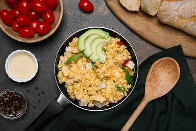 Photo of Frying pan with delicious scrambled eggs, tofu and avocado on black table, flat lay