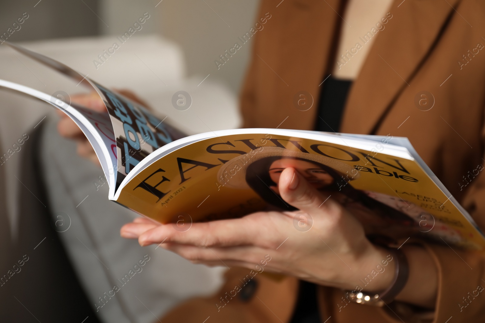 Photo of Woman reading fashion magazine on sofa at home, closeup