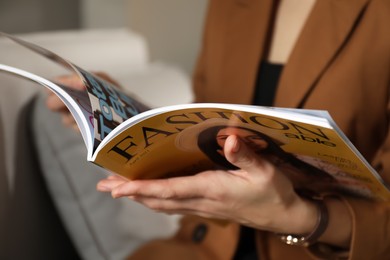 Photo of Woman reading fashion magazine on sofa at home, closeup