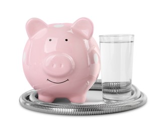 Photo of Water scarcity concept. Piggy bank, shower hose and glass of drink isolated on white