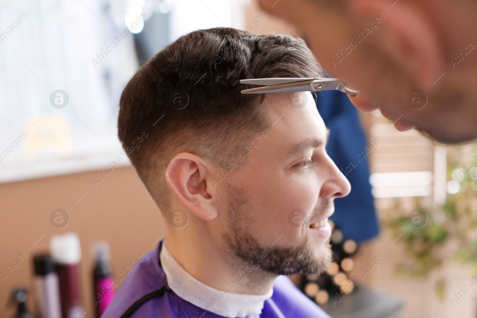 Photo of Professional hairdresser working with client in beauty salon, closeup