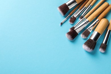 Photo of Different makeup brushes on light blue background, flat lay. Space for text