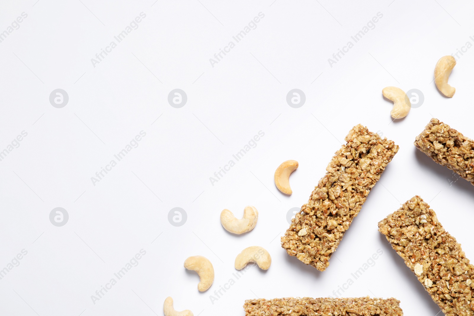 Photo of Tasty granola bars and cashew nuts on white background, flat lay. Space for text