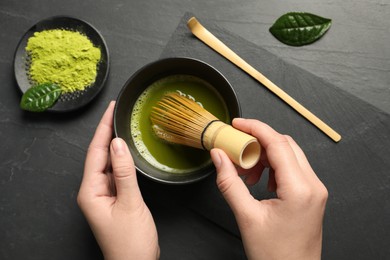 Woman preparing matcha tea at black table, top view