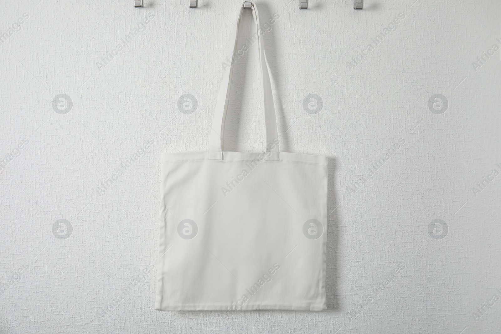 Photo of Tote bag hanging on white wall. Mock up for design