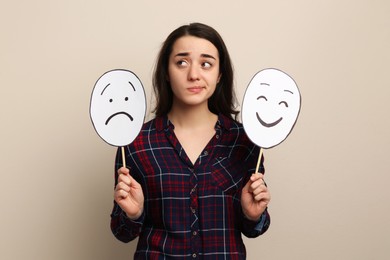 Photo of Woman with sad and happy paper faces on beige background