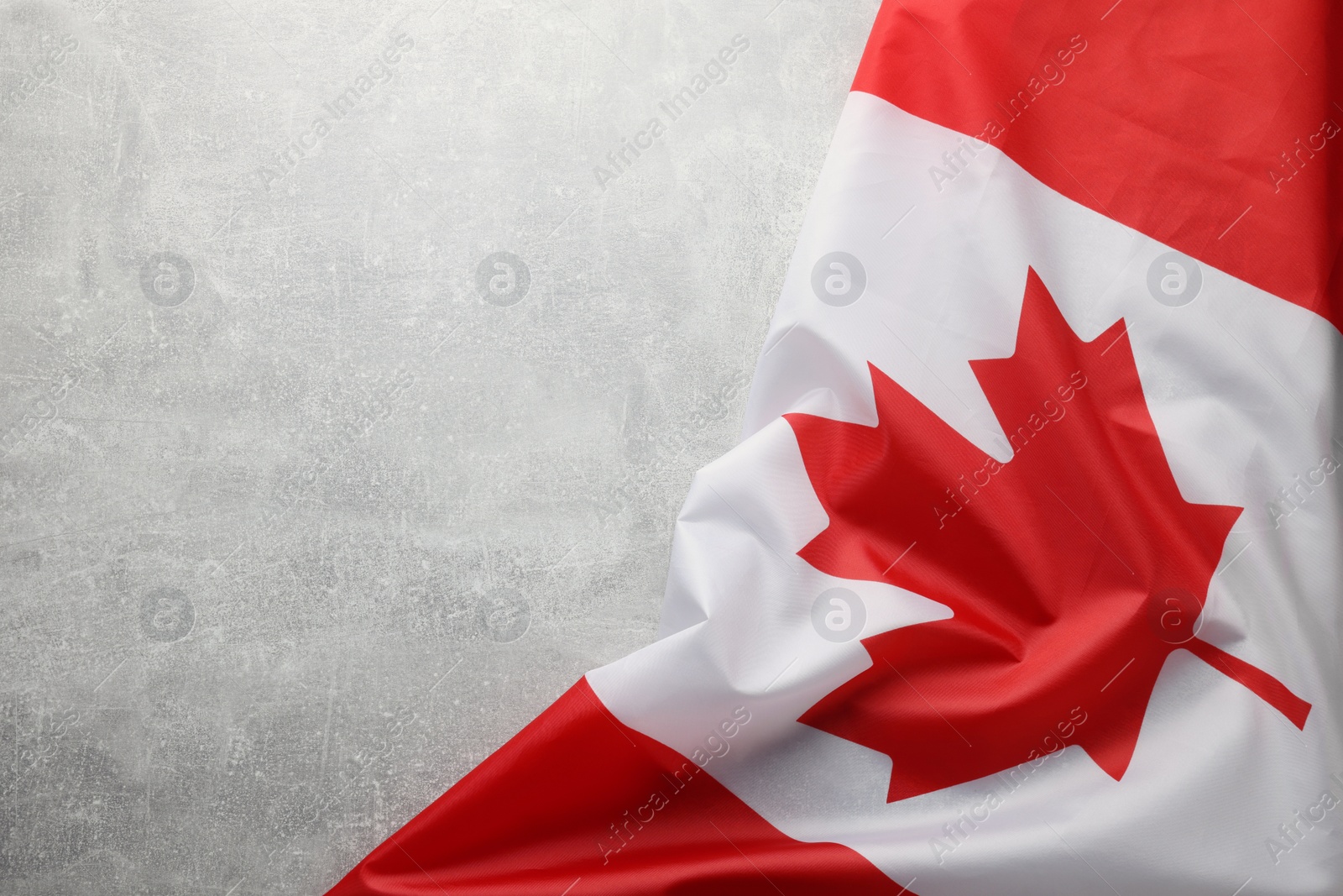 Photo of Flag of Canada on light grey stone table, top view. Space for text