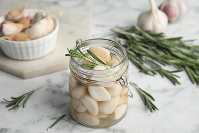 Composition with jar of pickled garlic on white marble table