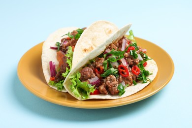 Photo of Delicious tacos with meat and vegetables on light blue table, closeup